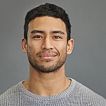 Smiling man in a gray sweater against background.