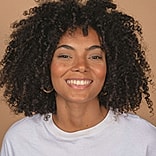 Smiling woman with curly hair and white shirt.