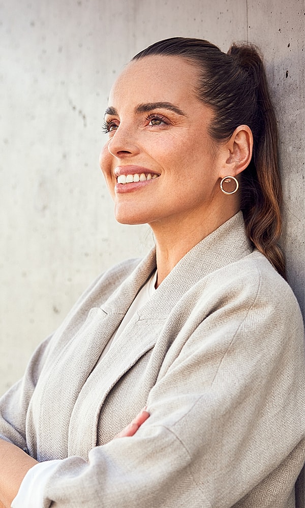 Smiling woman in a light-colored blazer.